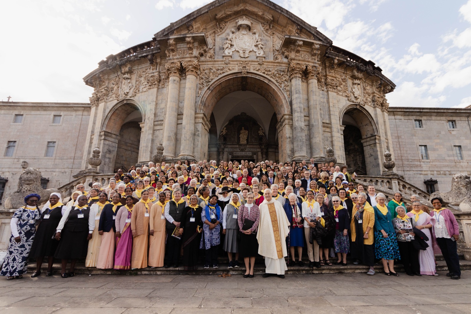 Grupo numeroso de irmãs do IBVM e da CJ reunidas nos degraus de um grande santuário em Loyola, posando para uma foto coletiva diante da fachada barroca do edifício.